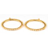 A pair of matching pearl set bangles, internal diameter 55mm, with screw and hinged opening,