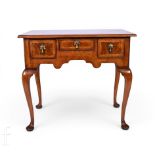 An 18th Century cross and feather banded walnut lowboy, fitted with three drawers, brass drop