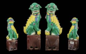 Pair of Chinese Antique Temple Lions, decorated in green enamels, on aubergine coloured bases.