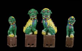 Pair of Chinese Antique Foo Dogs, decorated in green and yellow enamels on aubergine coloured bases.