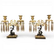A pair of Regency style bronze and ormolu two branch candelabra with glass drops, 26cm wide x 26.5