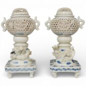 A pair of Japanese Hirado blue and white reticulated urns and covers decorated in relief with