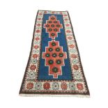 An Afghan wool runner, the blue field with two stepped geometric medallions within ivory geometric
