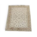 AN IVORY GROUND FINE PILE KASHAN RUG with all over floral/foliate patterned ground within beige