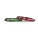 TWO ETERNITY RINGS both mounted in bright white metal, and set with calibre cut gemstones. Emerald