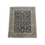 A DARK BLUE GROUND KASHAN RUG with all over floral/foliate patterned ground within dark blue