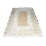 An Ivory ground Turkish rug with plain beige rectangular panel centre within geometric floral