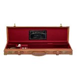 A BRASS-CORNERED TAN LEATHER SINGLE GUNCASE, fitted for 27in. barrels, the interior lined with red
