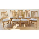 A set of seven blonde Ash Ercol Windsor Penn dining chairs with splat backs above padded seats and
