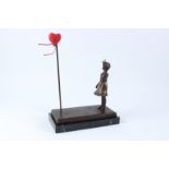 AFTER BANKSY. A bronze figure of a girl waving to a red heart shaped balloon, on a rectangular