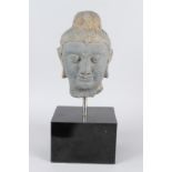 A CARVED STONE HEAD OF BUDDHA from the GANDHARA REGION. 20cms high, on a marble base