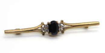 A 9ct gold and sapphire bar brooch, central oval sapphire flanked by trios of cz stones,