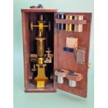 A mahogany cased R & J Beck brass monocular microscope with two eyepieces and three metal cased