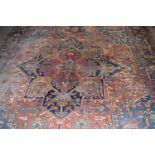 A large antique Middle Eastern wool floor rug with large central medallion on a rust and blue
