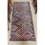 A Persian woollen Kelim rug, decorated with two rows of geometric motifs and having gull borders