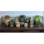 A collection of nine green and brown glazed studio pottery jugs, to include examples by A & J