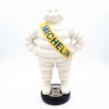 A reproduction painted cast iron model of the Michelin man, modelled standing on a tyre, h.38cm