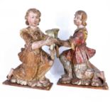 A pair of continental carved and polychrome painted angel altar candleholders, as kneeling