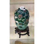 An oriental blue ground vase with embossed floral decoration on wooden base Wear near top and to