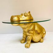 HIPPO LOW TABLE IN A GILT FINISH WITH GLASS TOP.