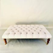 HEARTH STOOL WITH DEEP BUTTONED NEUTRAL LINEN UPHOLSTERY ON TURNED SUPPORTS.