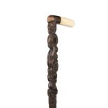 A Maori walking stick with a bone handle and abalone shell inlaid eyes 89cm high