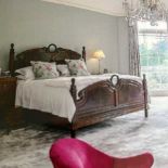 A large early 20th century French walnut bedstead, with scrolled panels, turned finials and a padded