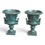 A pair of green painted cast iron garden urns, each of campagna shape, on a socle base, 59cm high (