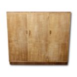 A Heals Art Deco to mid-century limed oak three door cupboard, set upon a rectangular platform,