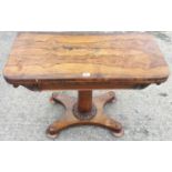 A William IV rosewood fold over games table on turned column with carved collar and quatrefoil