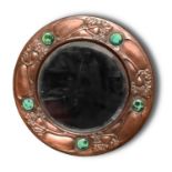 An Arts and Crafts circular copper repousse mirror, possibly Liberty & Co, c1905, decorated with