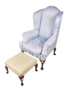 A high wing back armchair and a footstool.