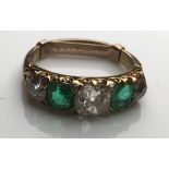 A yellow metal mounted diamond and emerald five stone ring, the centre stone approx. 0.