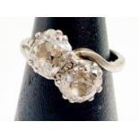 An 18ct white gold and platinum diamond ring, claw-set with two Victorian-cut diamonds in a twist