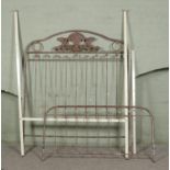 A partially painted metal double bed frame decorated with bird and foliage motifs.