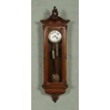 A large walnut cased twin-weight Vienna wall clock with ornately carved pediment. The silvered