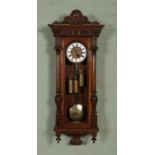 A walnut cased Gustav Becker triple weight Vienna wall clock, with carved pediment and reeded