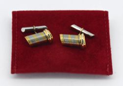 Cartier, a pair of gold and steel barrel design cufflinks, marked Cartier 407591, with red cloth