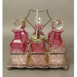 Graduated clear to cranberry glass six-piece cruet set on a rectangular silver-plated stand raised