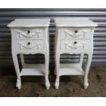 A pair of modern, painted white 2-drawer bedside tables, with lower tier shelf to each, swag and bow