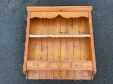 A pine delft rack with moulded cornice above shaped apron and open shelves, having tongue-and-