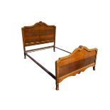 An oak double bed with arched headboard and tailboard surmounted by carved shell crests, raised on