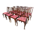 A set of twelve Chippendale style mahogany dining chairs with shaped scalloped backs above leaf