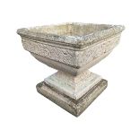 A square composition stone garden urn with moulded rim above a frieze cast with stylised foliage, on