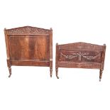 A C19th French walnut bedhead and footboard, the headboard pediment with central urn carved panel