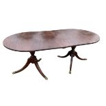 A regency style mahogany dining table, with D-end top with reeded edge and extension leaf, on twin