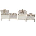 A pair of French Louis XVI style gilded & painted single beds with floral carved arched crestrails
