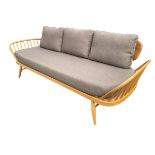 An Ercol windsor style beech daybed sofa with boarded back and rounded arms on spindles framing