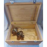 A pine storage box containing a small brass oil lamp base, two glass chimneys and two pewter mugs/