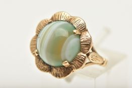 A 9CT GOLD AGATE CABOCHON RING, in the form of a flower set with a central circular cut green banded